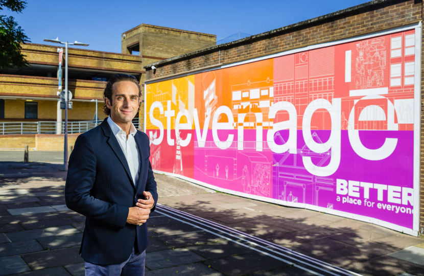 Alex Clarkson standing in front of the large 'Stevenage' sign in Stevenage town centre