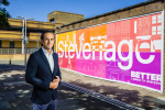 Alex Clarkson standing in front of the large 'Stevenage' sign in Stevenage town centre