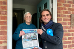 Alex Clarkson meeting with an elderly resident on their doorstep, they are both holding up one of Alex's leaflet